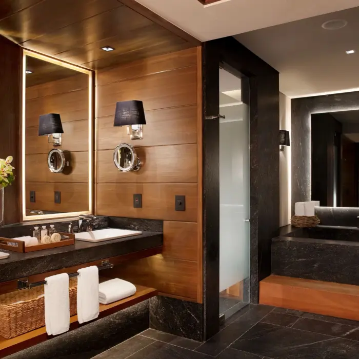 Luxurious bathroom with dual vanities, soaking tub, and dark stone finishes in the Signature Suite.