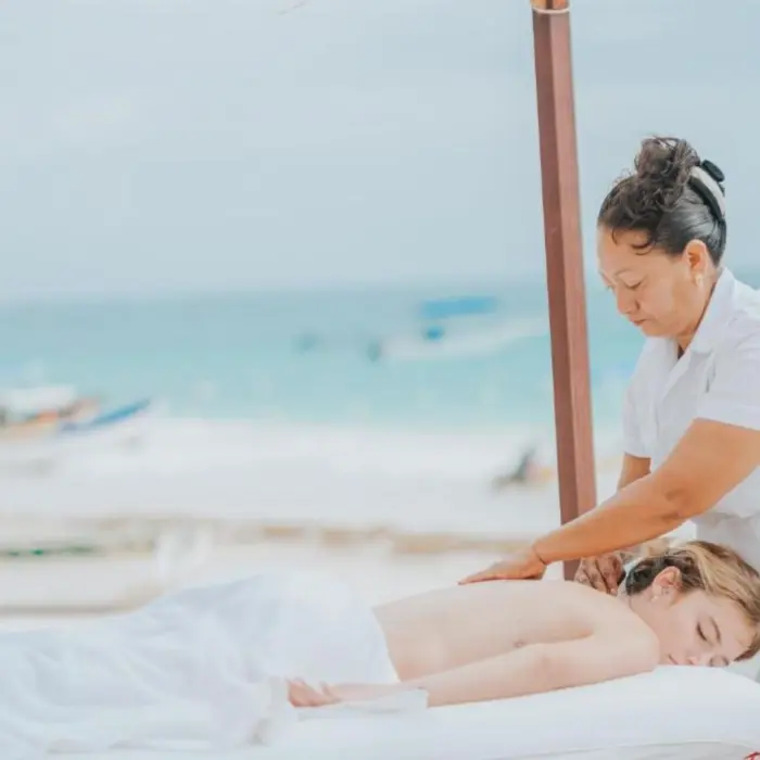 A woman receiving a relaxing beachside massage at Kai Tulum Hotel spa, with the ocean in the background.