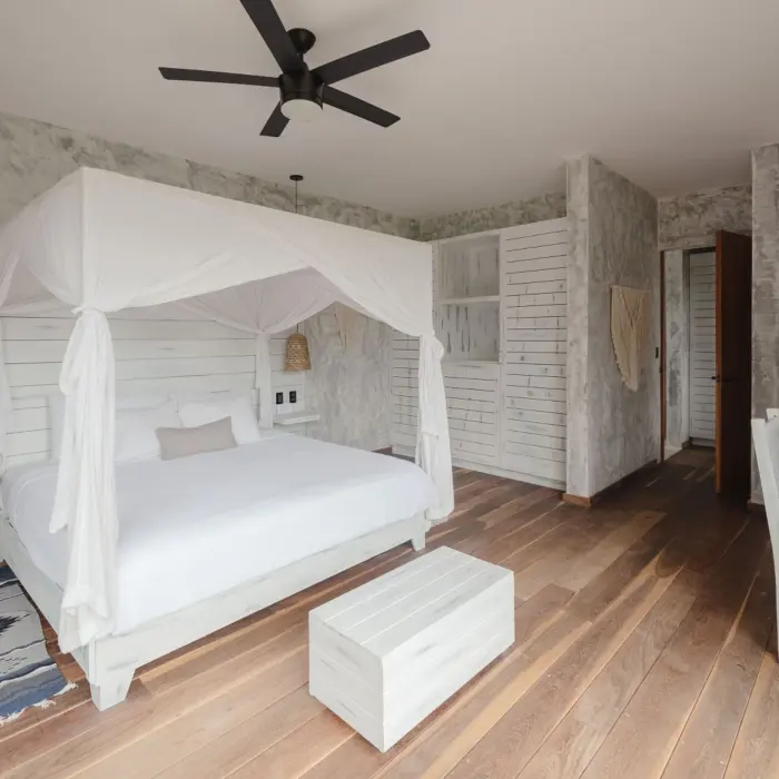 The interior of a Premium Garden View Suite at Kai Tulum Hotel, with a canopy bed and rustic-chic decor.
