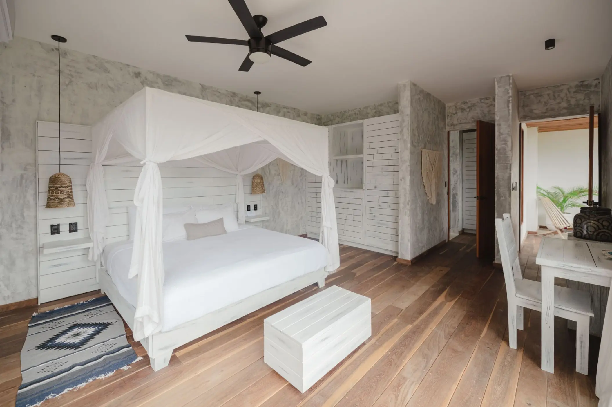 The interior of a Premium Garden View Suite at Kai Tulum Hotel, with a canopy bed and rustic-chic decor.