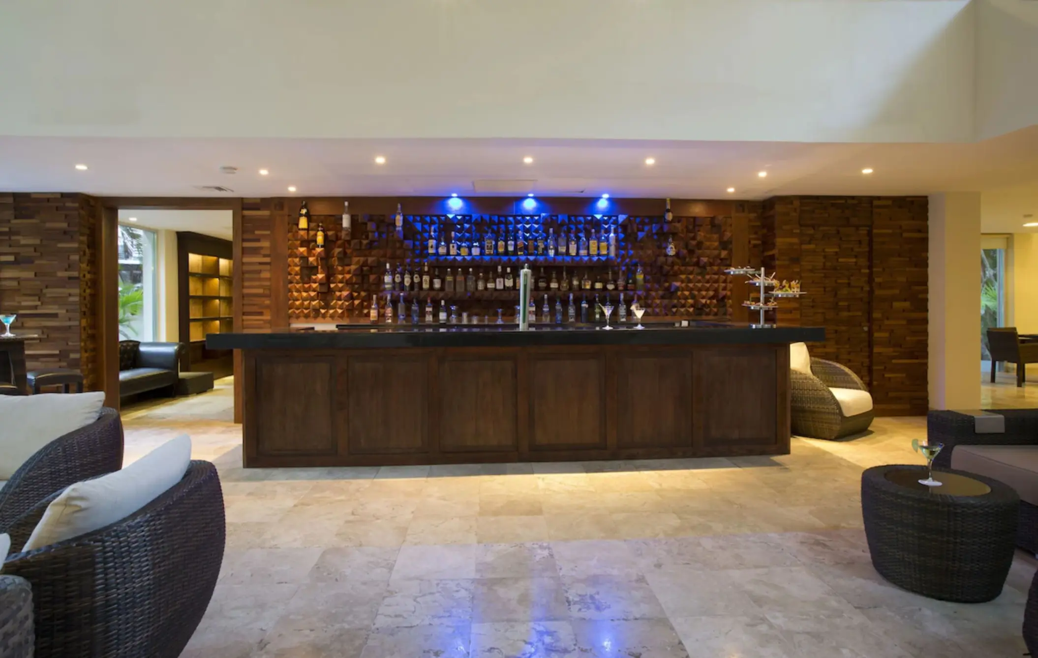 A stylish hotel bar with a long wooden counter, a well-stocked liquor display, and comfortable seating.