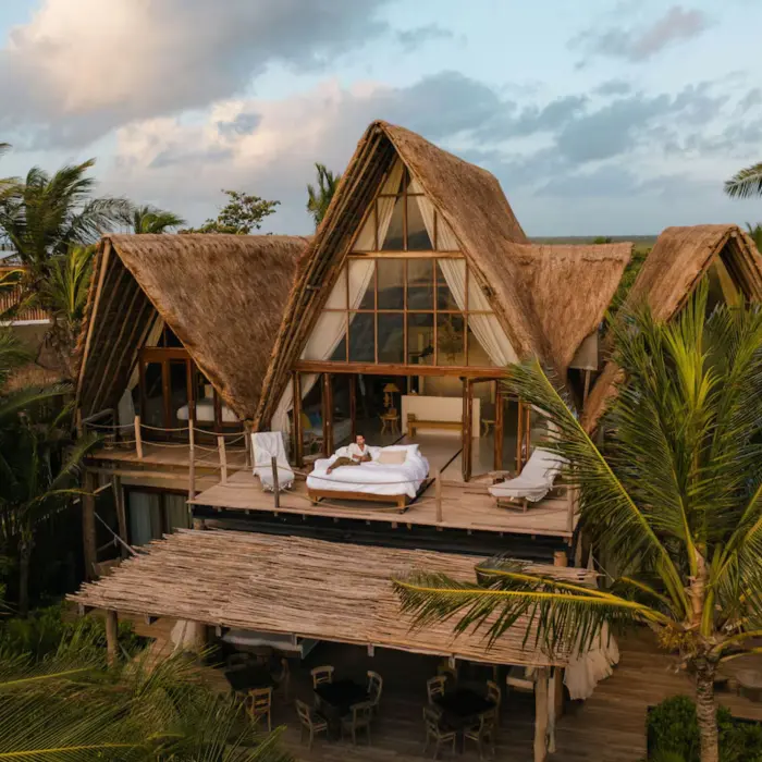 woman sitting on a bed on the terrace of her suite at La Valise Tulum