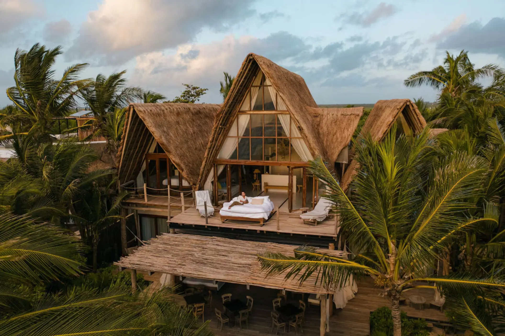 woman sitting on a bed on the terrace of her suite at La Valise Tulum