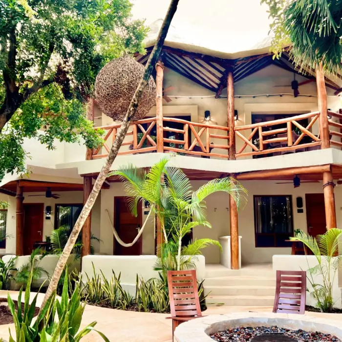 Two-story villa with balcony, hammocks, and a jungle garden courtyard at tropical boutique resort.