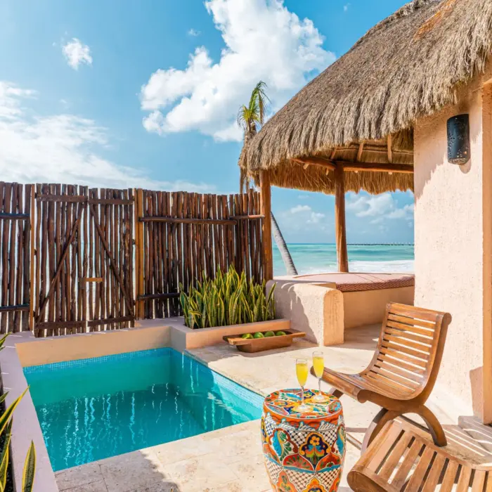 Private beachfront plunge pool and lounge area with wooden deck and tropical fence.
