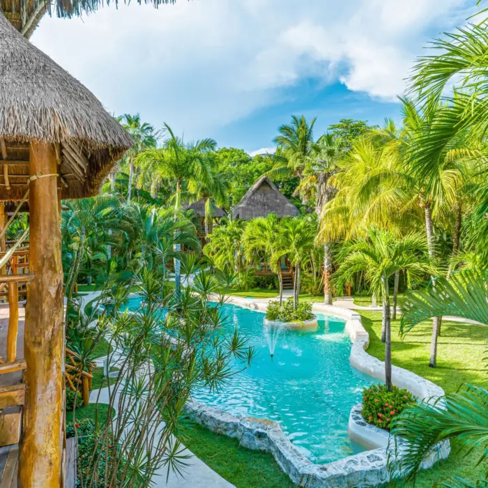 Lagoon-style pool meandering through lush tropical gardens and palm trees with hammock-lined balconies.