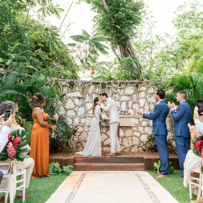 Romantic wedding ceremony in a jungle garden with and stone backdrop.