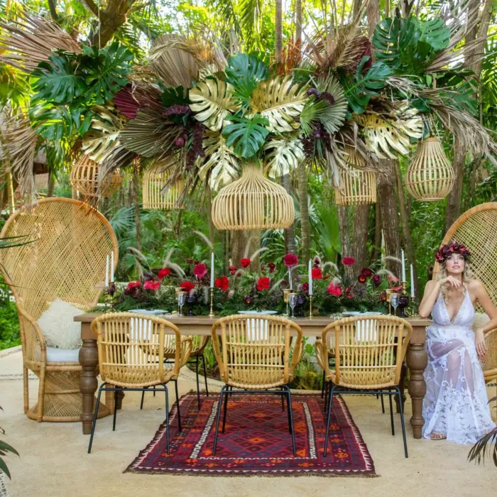 Boho-chic jungle wedding setup with oversized peacock chairs, tropical florals, and hanging basket lanterns.