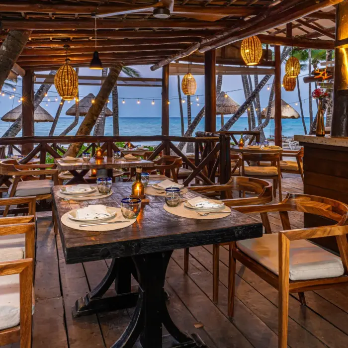 Cozy beachfront restaurant with ocean views, wooden furnishings, and soft candlelight for romantic dining.