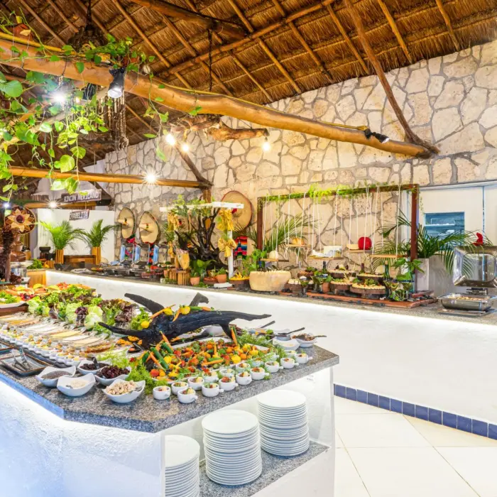 Traditional Mexican buffet setup with colorful dishes, handmade decor, and fresh ingredients under a palapa-style roof.