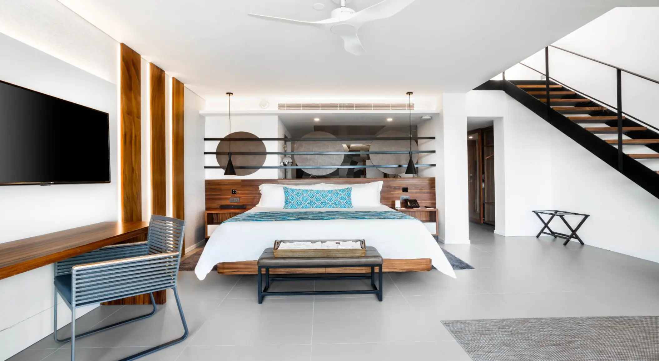 Bright two-story suite with king bed, large mirror decor, and modern wood furnishings.