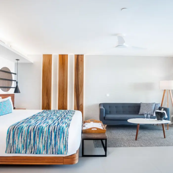Bright suite with king bed, modern decor, and sitting area near sliding doors to balcony.