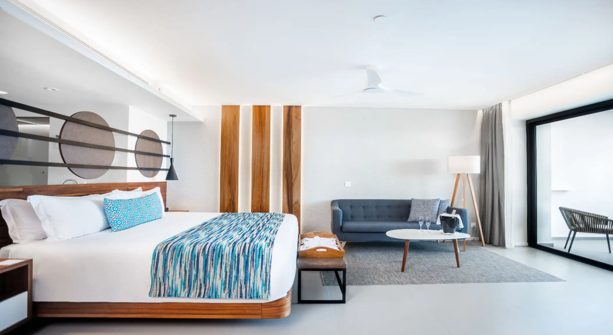 Bright suite with king bed, modern decor, and sitting area near sliding doors to balcony.