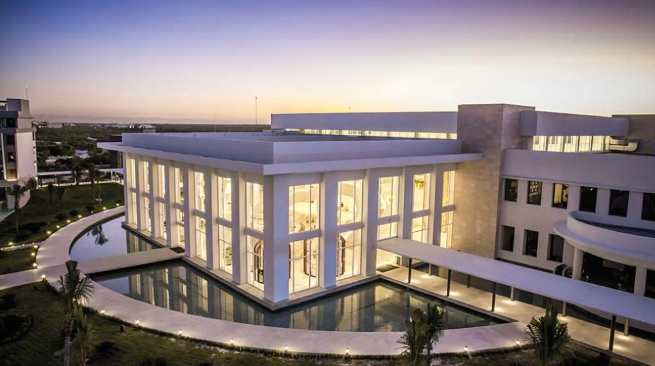 Stunning event venue lit by sunset, surrounded by water and tropical landscaping at Majestic Costa Mujeres.