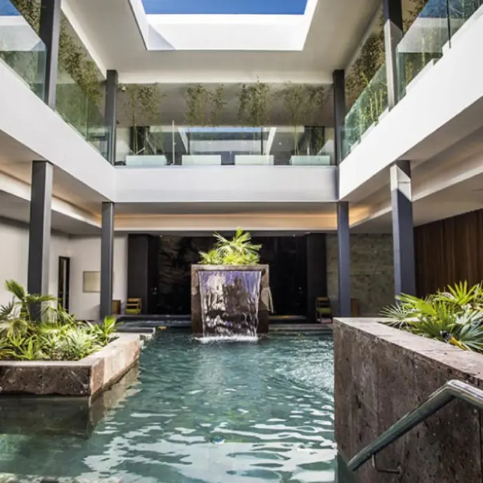 Indoor spa pool with waterfall feature, tropical plants, and natural lighting at Majestic Elegance Costa Mujeres.