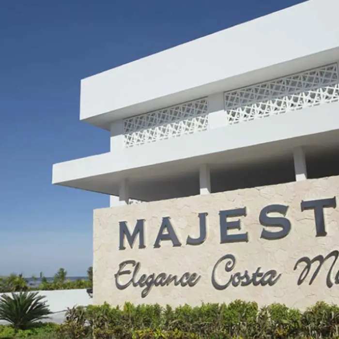 Exterior sign of Majestic Elegance Costa Mujeres against a clear blue sky near the resort’s entrance.
