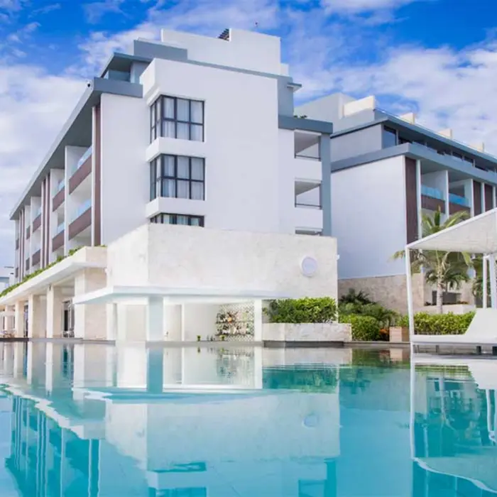 Infinity-edge pool with modern architecture and shaded lounge beds at Majestic Elegance Costa Mujeres.
