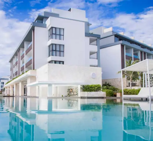 Infinity-edge pool with modern architecture and shaded lounge beds at Majestic Elegance Costa Mujeres.