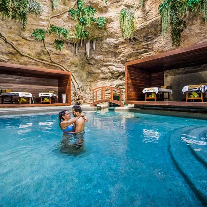 Romantic spa nestled in a natural cave with massage beds, water features, and lush hanging vines.