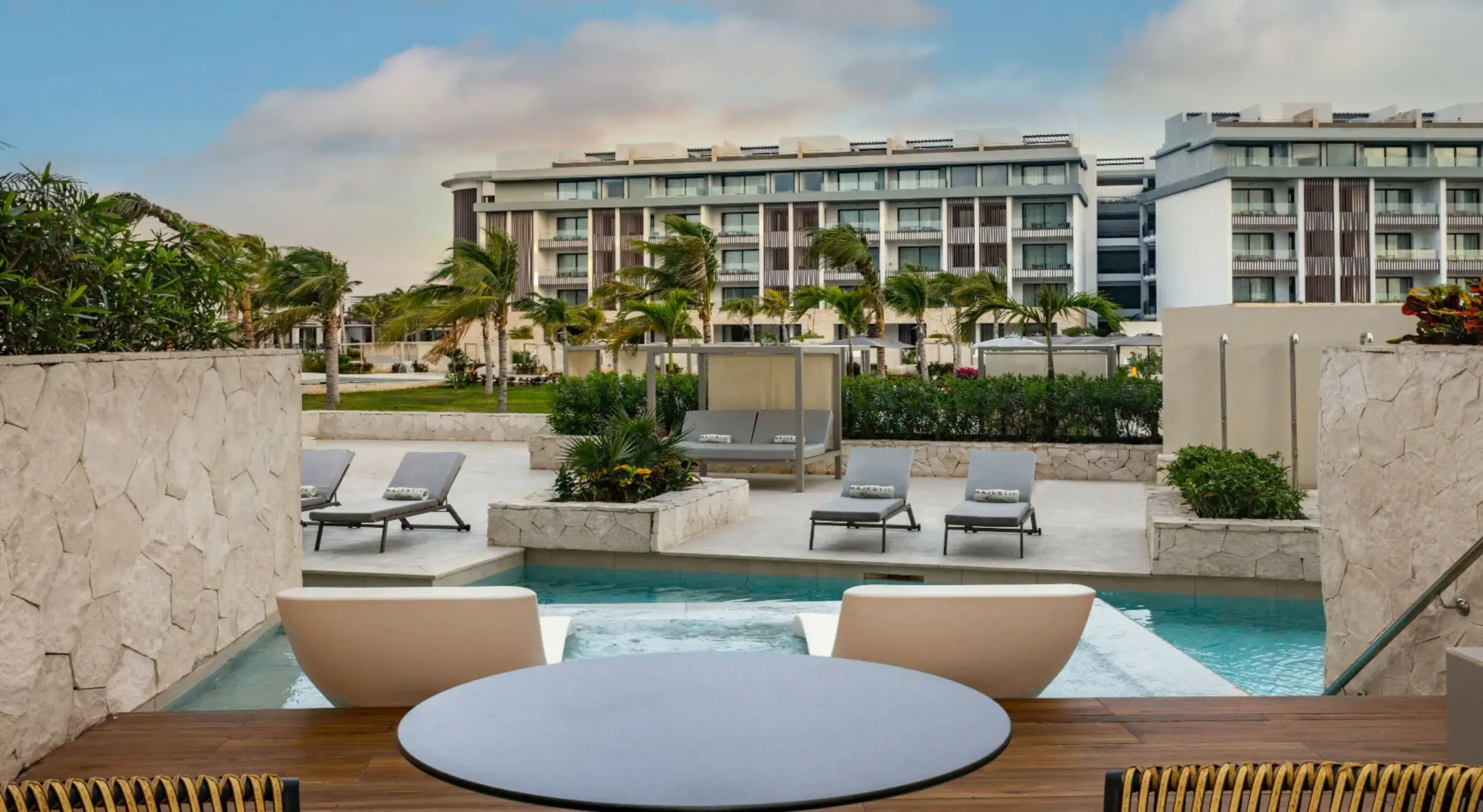 Swim-up suite with modern loungers and direct pool access, overlooking the resort gardens and suites.