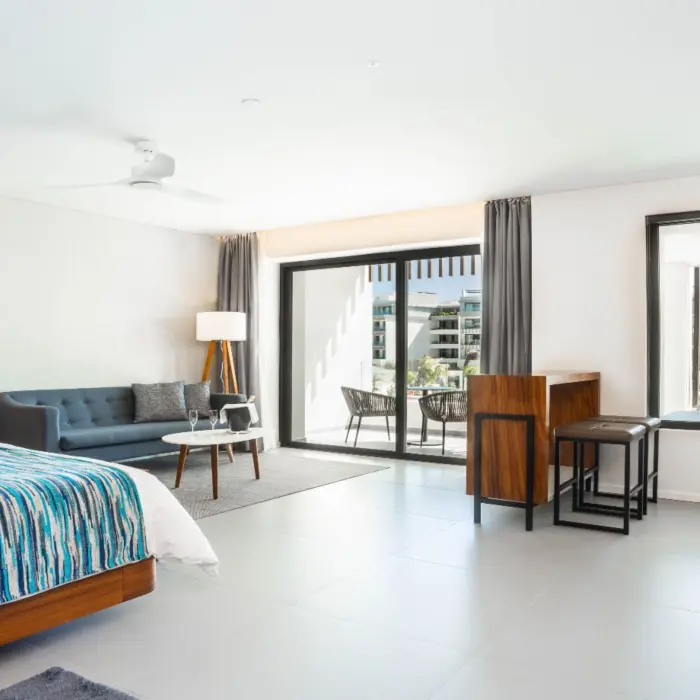Spacious suite with king bed, sofa, work desk, and balcony view.