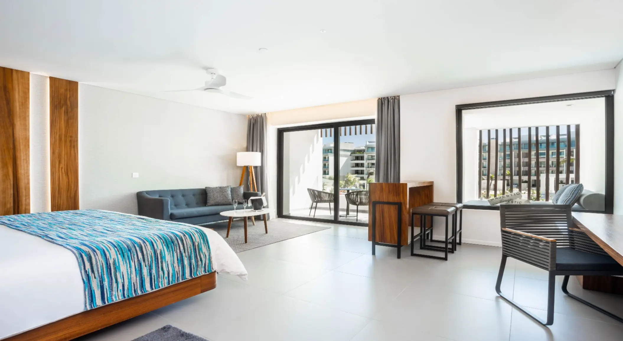 Spacious suite with king bed, sofa, work desk, and balcony view.