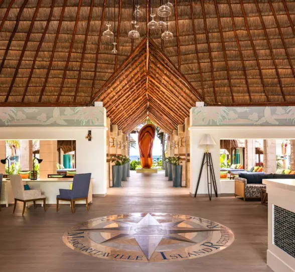 Open-air lobby with thatched roof, ocean views, stylish seating areas, and tropical-inspired design details.