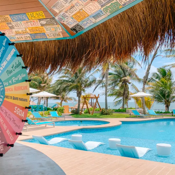 Colorful margarita wheel at bar overlooking poolside lounge chairs and ocean view.