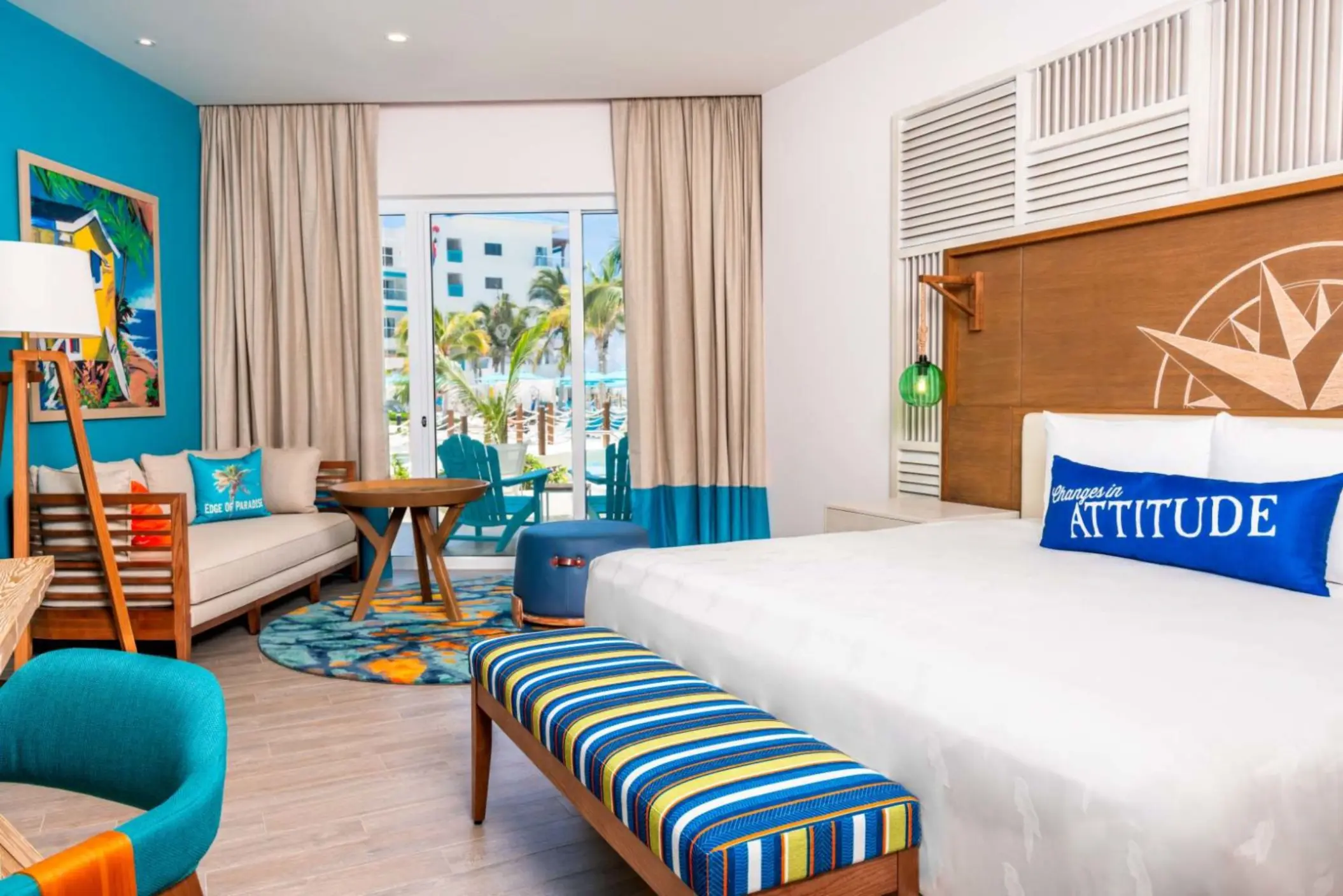 Spacious suite with king canopy bed, neutral tones, and patio access with views of lush tropical gardens.