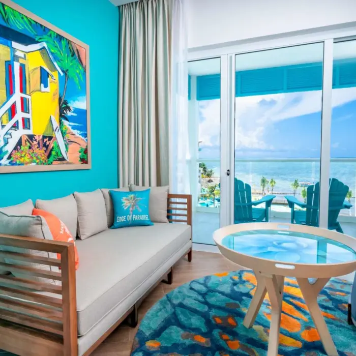 Oceanview suite with elegant four-poster bed, seating nook, and terrace overlooking the Caribbean Sea.