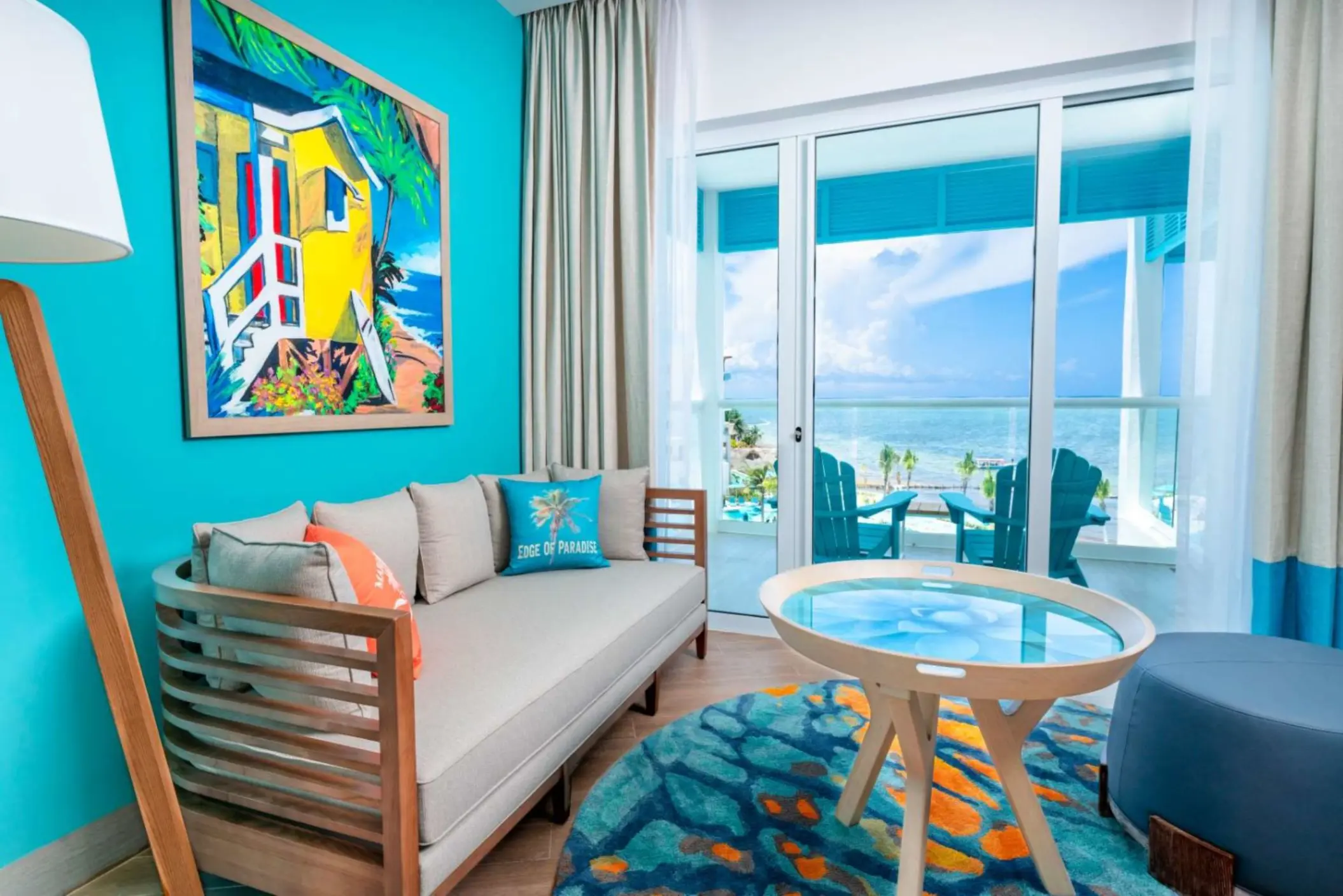 Oceanview suite with elegant four-poster bed, seating nook, and terrace overlooking the Caribbean Sea.