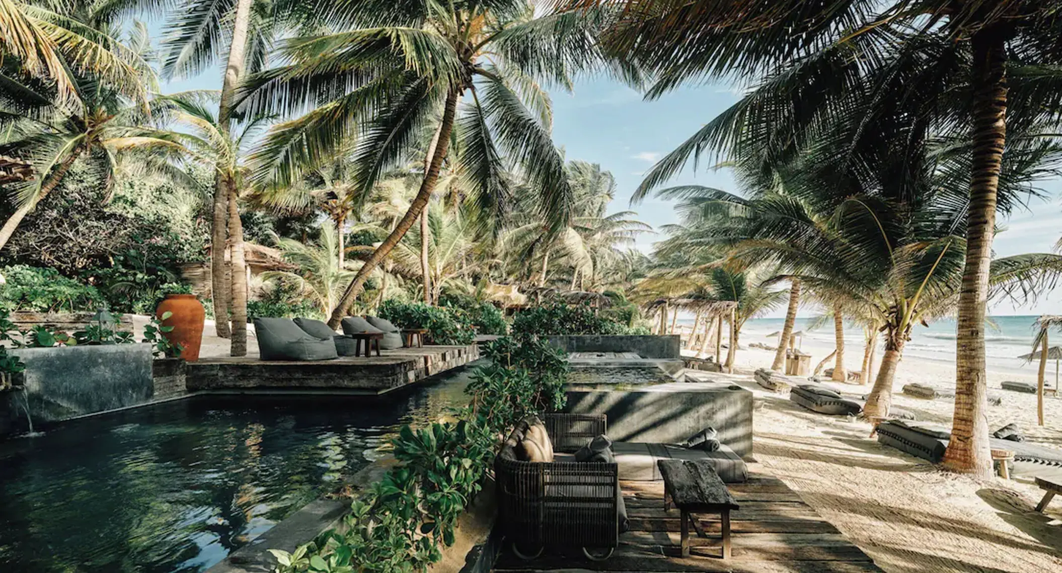 beachfront pool with sofas and loungers at nomade tulum