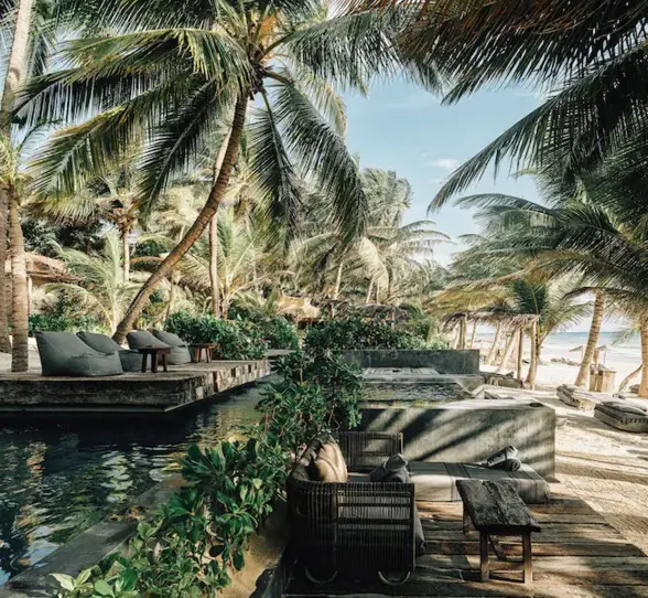 beachfront pool with sofas and loungers at nomade tulum
