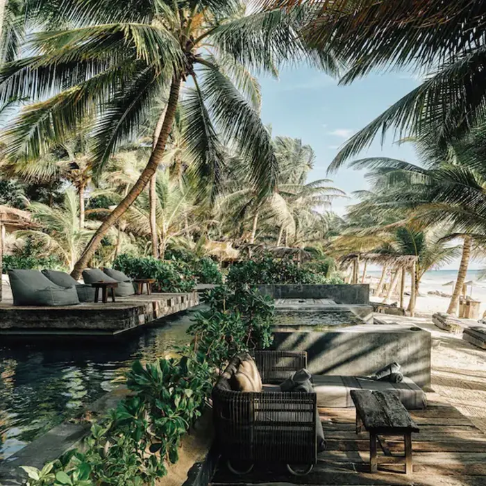 beachfront pool with sofas and loungers at nomade tulum