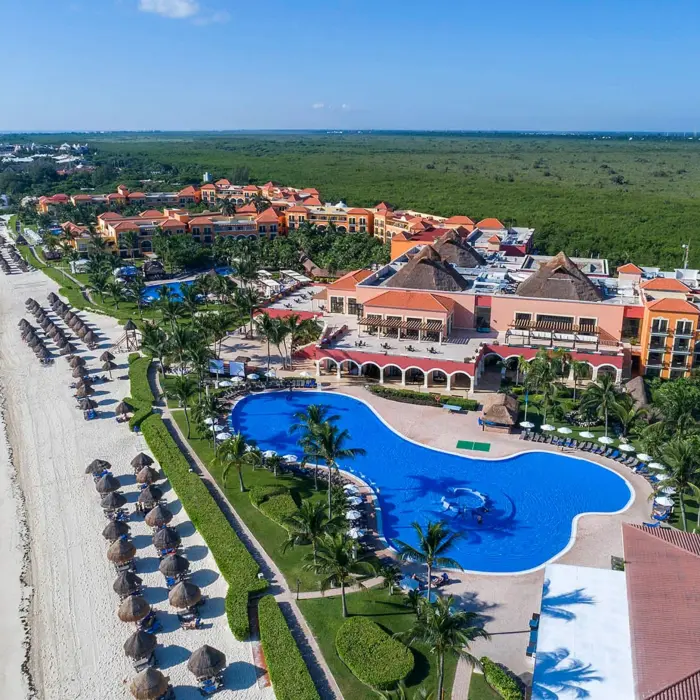 An aerial shot of the resort, showcasing the large winding pool, white sand beach, and ocean.