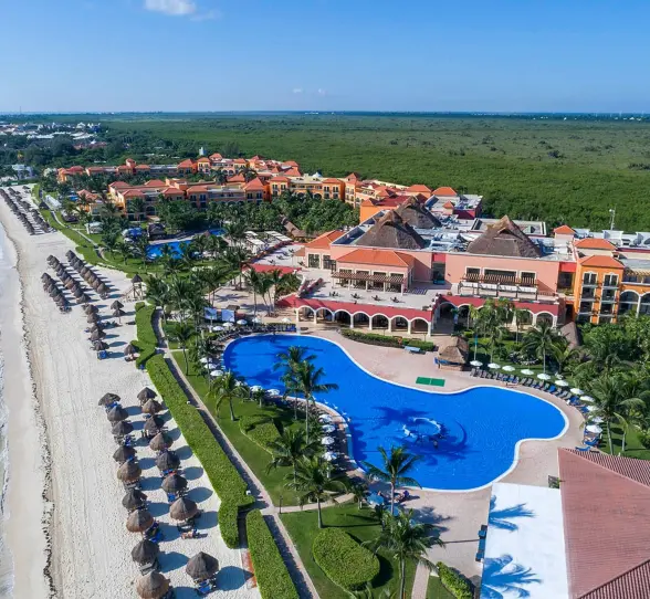 An aerial shot of the resort, showcasing the large winding pool, white sand beach, and ocean.