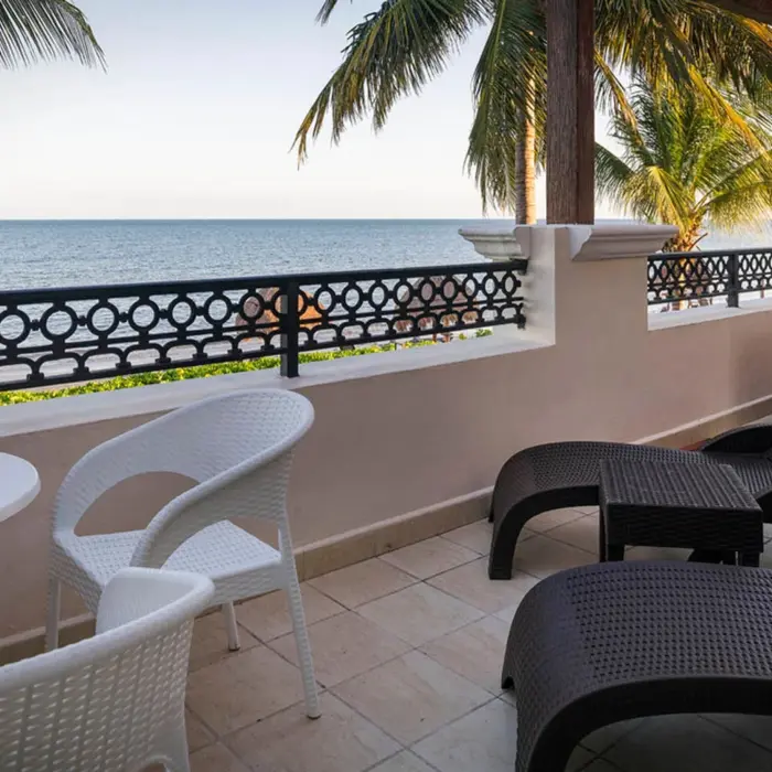 An ocean-view balcony with a private hot tub, lounge chairs, and a table with chairs.