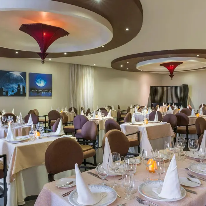 An elegant restaurant with multiple tables set for dinner and a sophisticated, modern decor.