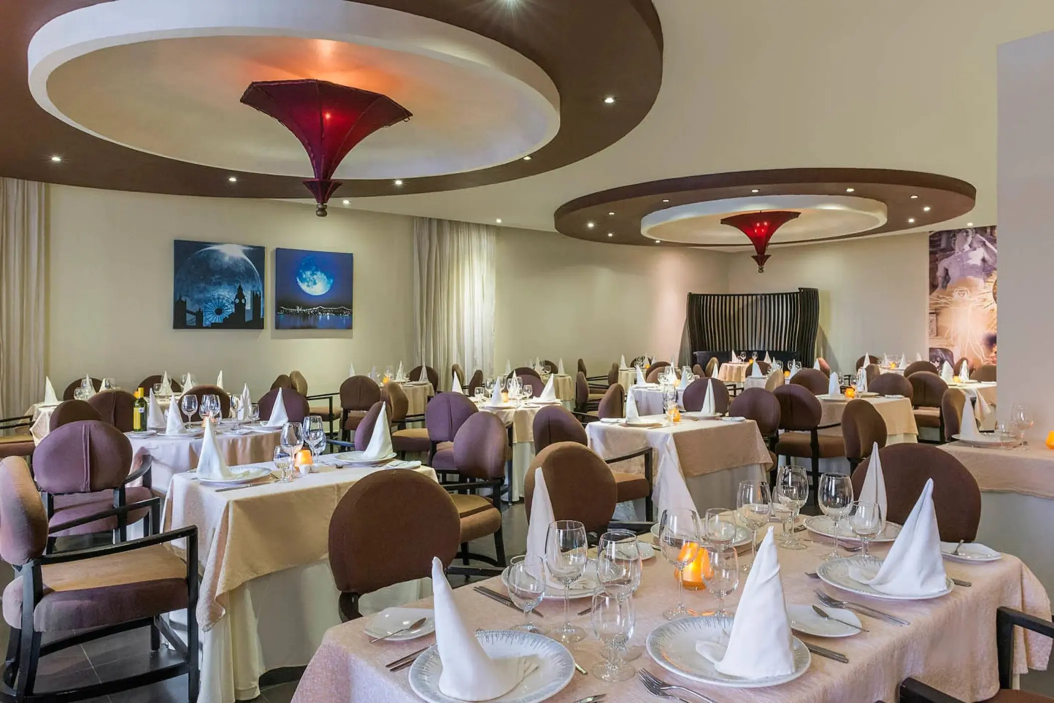 An elegant restaurant with multiple tables set for dinner and a sophisticated, modern decor.