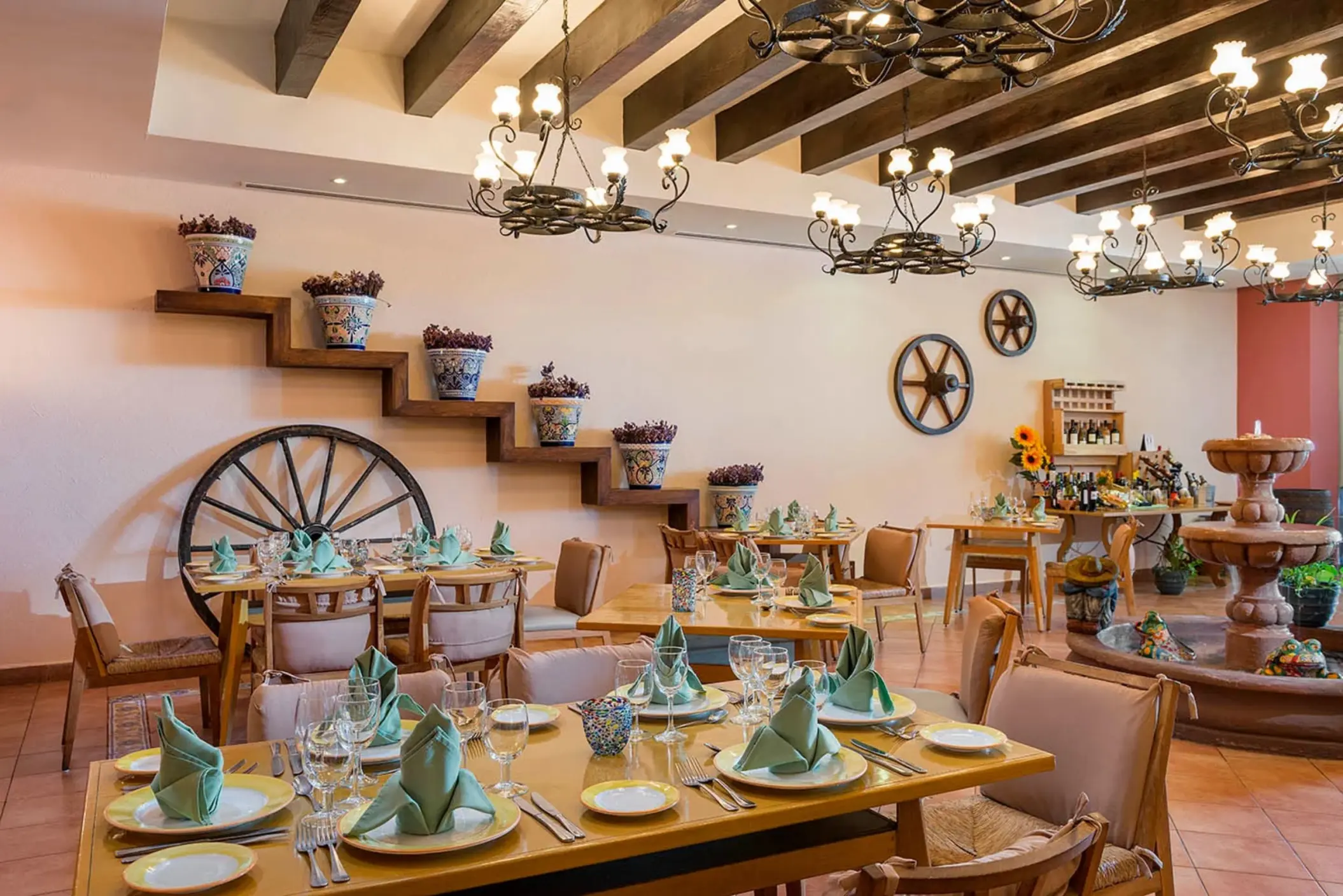 A restaurant with rustic, hacienda-style decor, including wooden beams and a large decorative fountain.