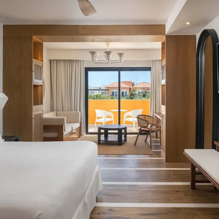 A junior suite with a bed, a living area, and a balcony with outdoor seating.