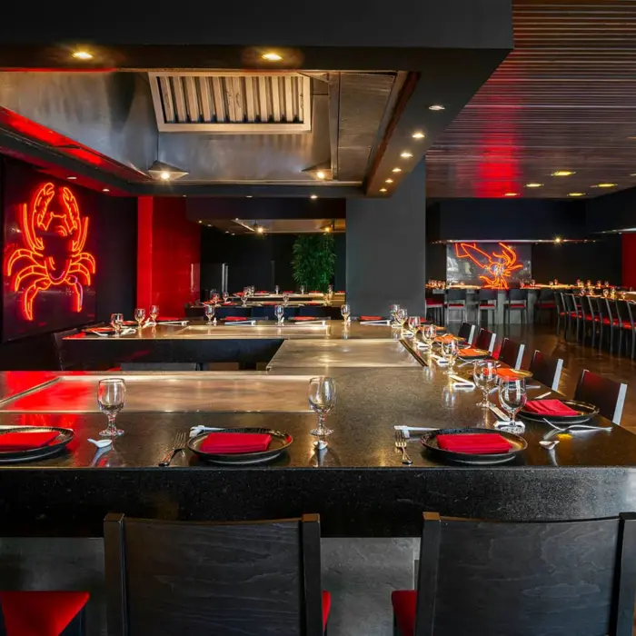 A modern Teppanyaki restaurant with a black and red color scheme and a neon crab sign.