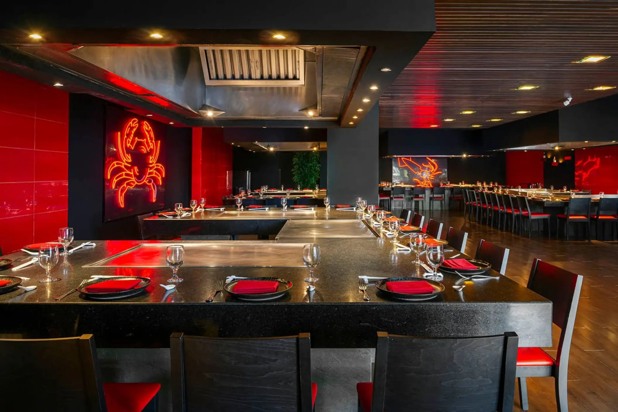 A modern Teppanyaki restaurant with a black and red color scheme and a neon crab sign.