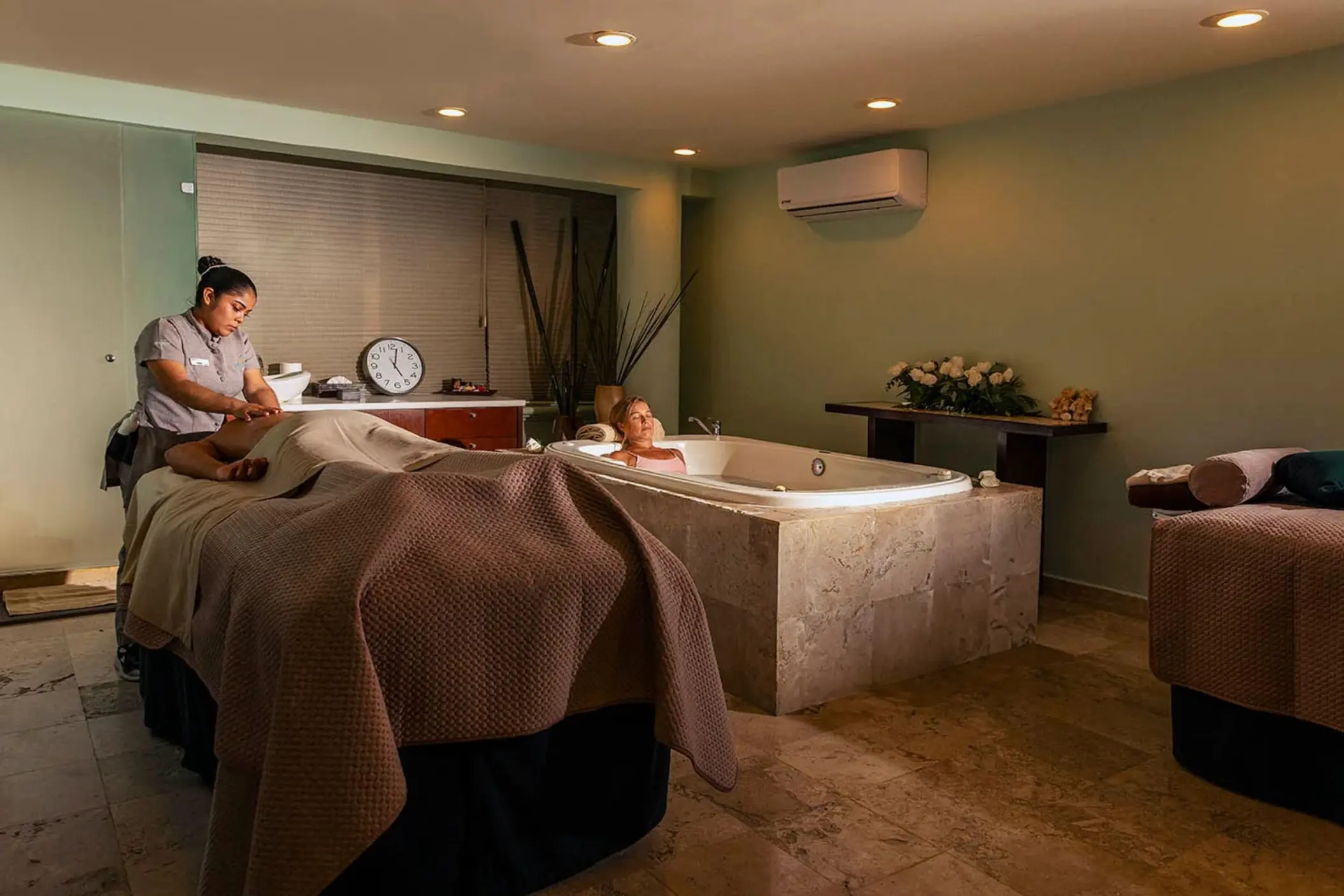 tranquil spa treatment room with a person receiving a massage, a relaxing bath, and serene lighting, surrounded by soothing decor.