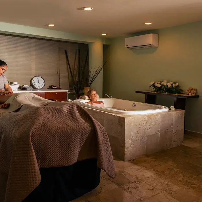 tranquil spa treatment room with a person receiving a massage, a relaxing bath, and serene lighting, surrounded by soothing decor.