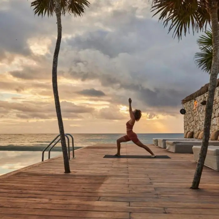 woman doing yoga on the poolside deck at Our Habitas Tulum