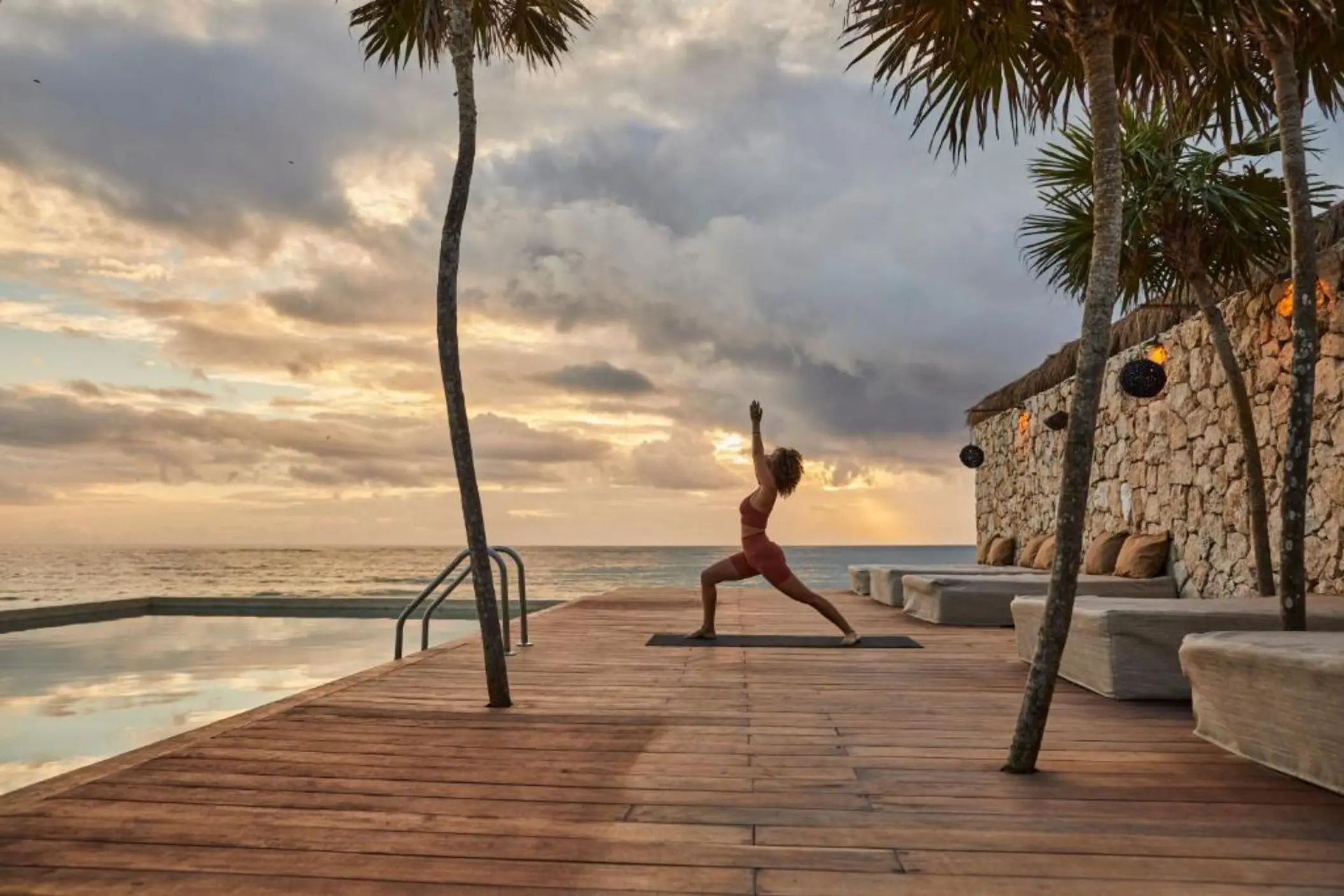woman doing yoga on the poolside deck at Our Habitas Tulum