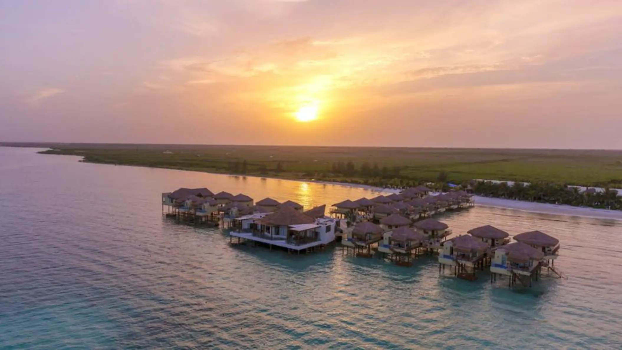 sun setting over Palafitos Overwater Bungalows and the sea