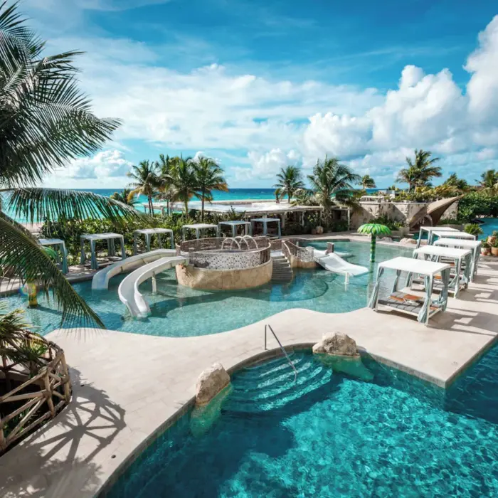 Multi-level outdoor swimming pools surrounded by tropical greenery at Palmaïa – The House of AïA in Riviera Maya