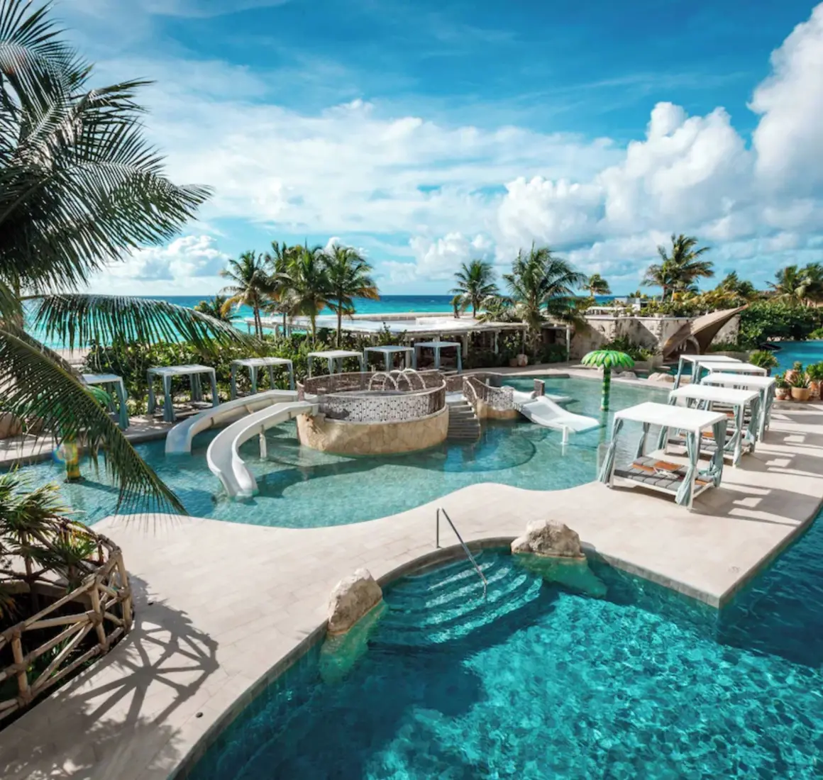 Multi-level outdoor swimming pools surrounded by tropical greenery at Palmaïa – The House of AïA in Riviera Maya
